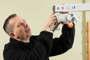 Care worker using a mobile hoist in a Derbyshire care home during LOLER testing.