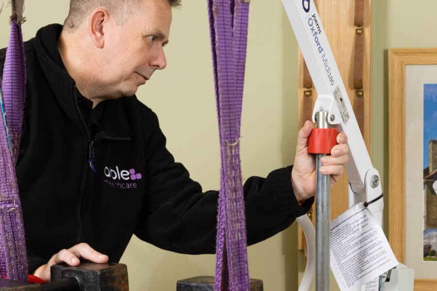 Technician performing safe working load test on hoist during LOLER inspection in care home