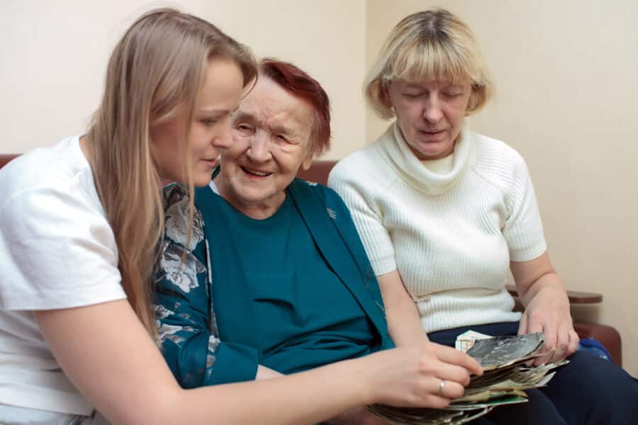 Three women sharing photos together in a care home, illustrating family visits during festive periods.